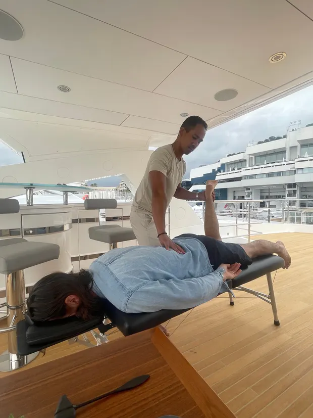 Dr. Rodante Saballa treating a client on a portable table on a yacht deck.